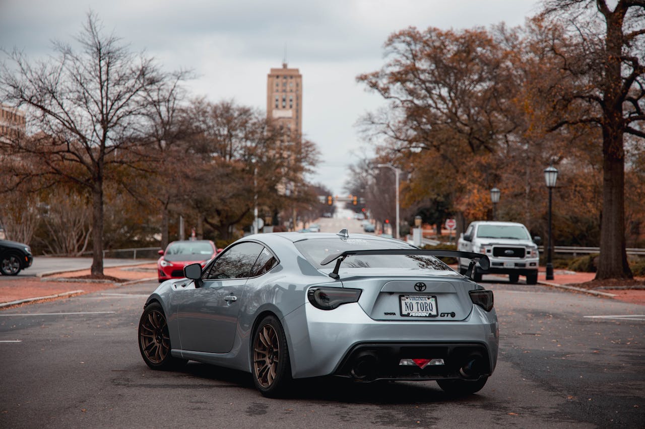 A silver sports car parked on a tranquil city street in winter surroundings.